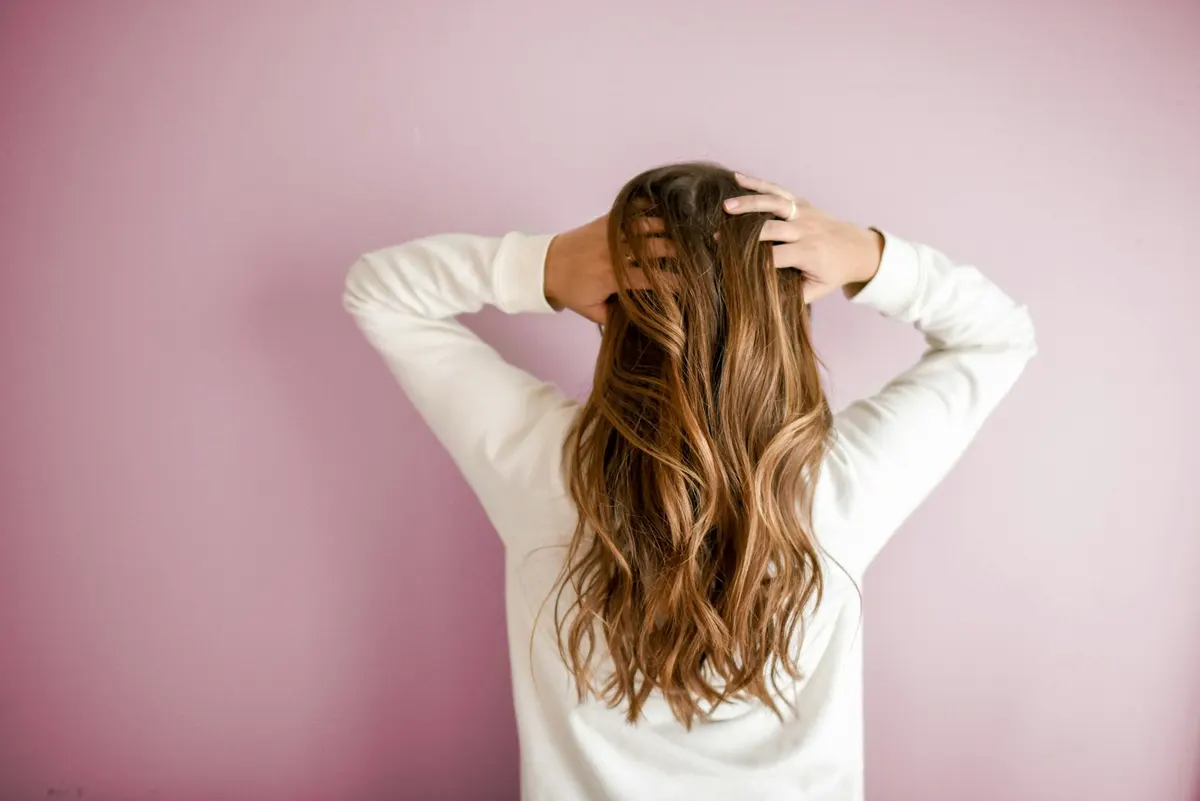 A woman running both hands through long, glossy hair