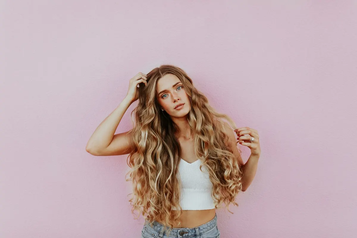 Long, tousled waves against a blush backdrop