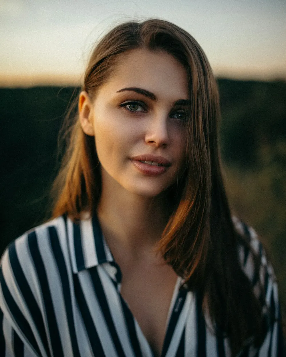 A woman with long, healthy-looking hair in warm evening light